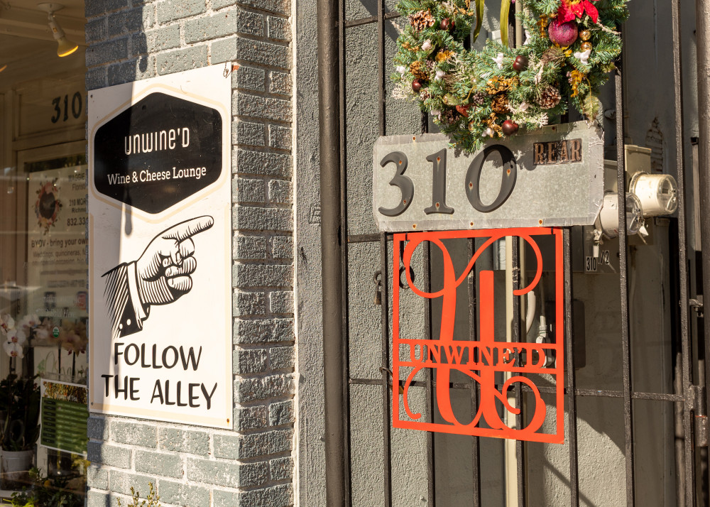 Iron Gate with Unwine'd sign, address, and separate sign saying "follow the alley."