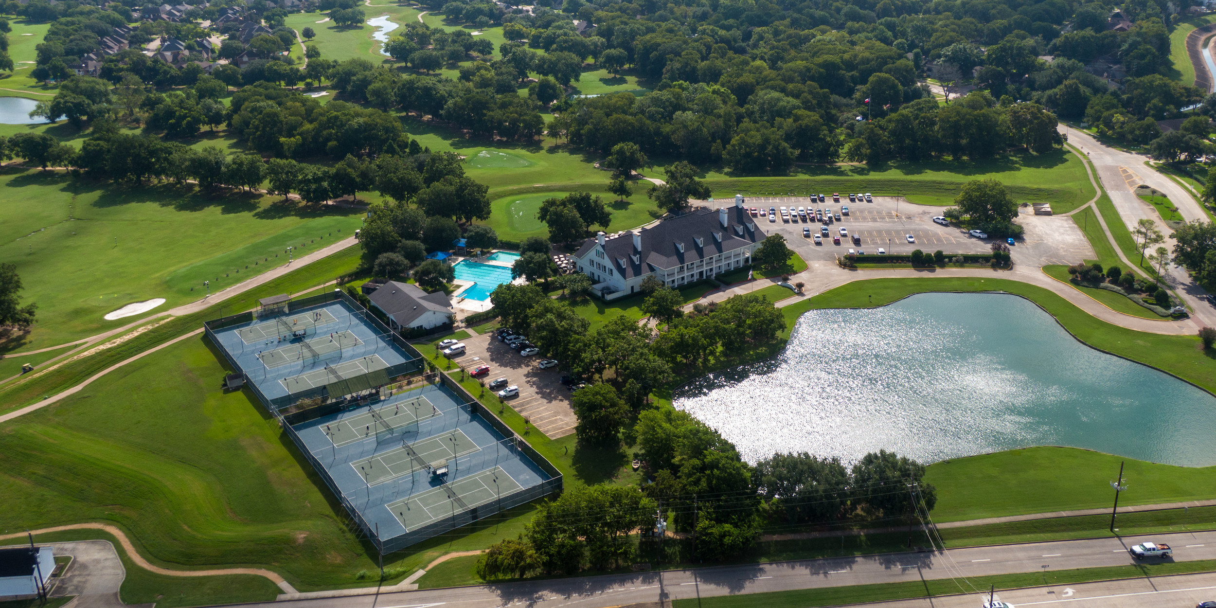 Aerial view of facility with tennis courts, pool, and golf courses in the background