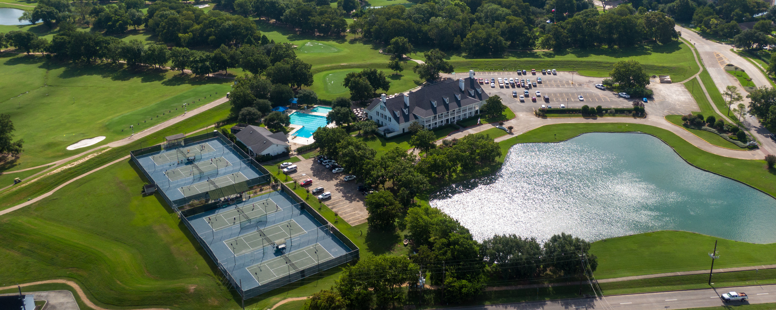 Aerial view of facility with tennis courts, pool, and golf courses in the background