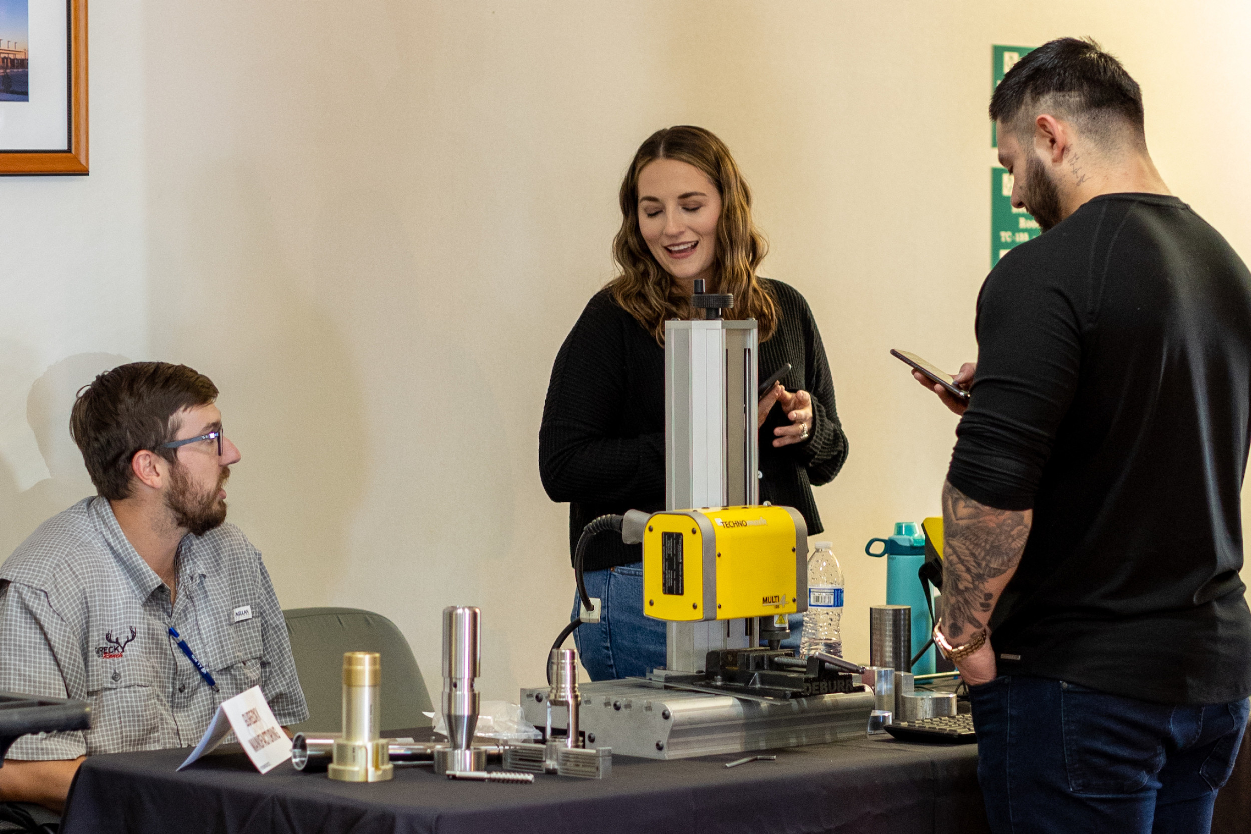 Workers conversing over machinery at a booth